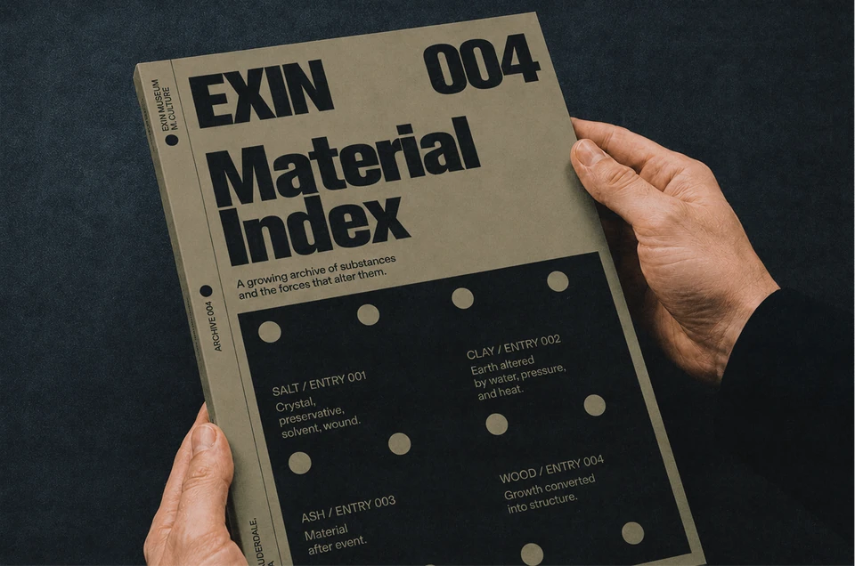 A hand holds the olive-green Exin Material Index publication, numbered 004.