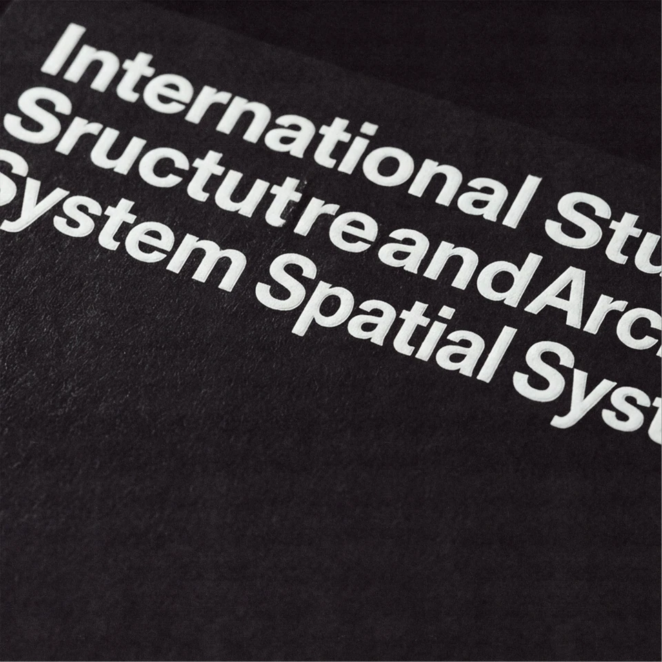 Close-up of white typographic lettering describing the architectural studio on black fabric.