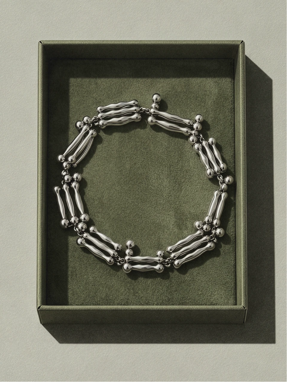 Silver chain bracelet displayed in an olive-green presentation tray.