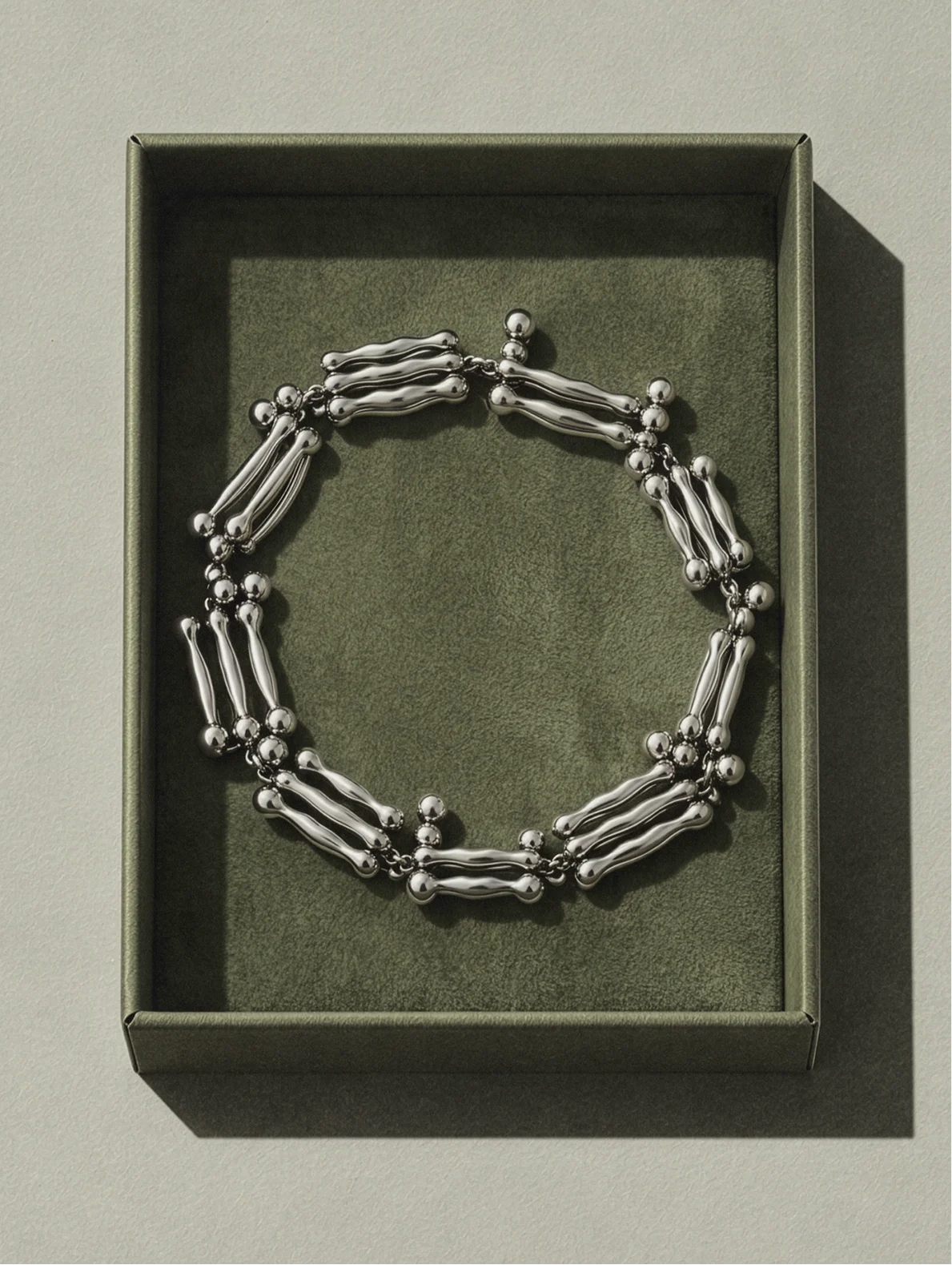 Silver chain bracelet displayed in an olive-green presentation tray.